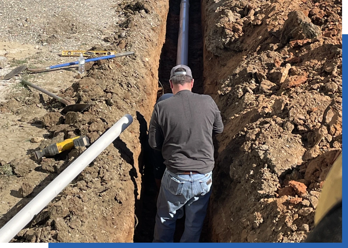 Worker installing pipe in trench